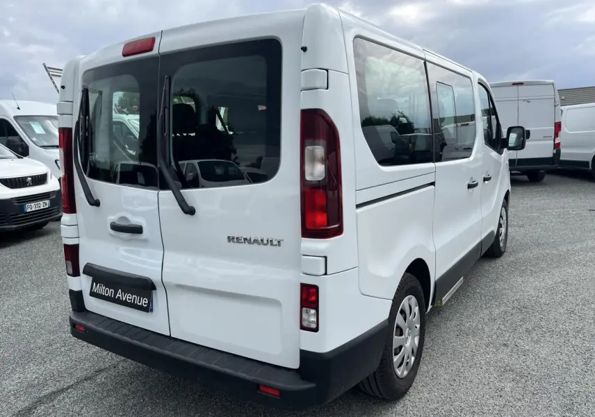 Renault Trafic Fourgon blanc vu en 3/4 arrière droit, avec portes arrière vitrées et pare-chocs noirs grainés.