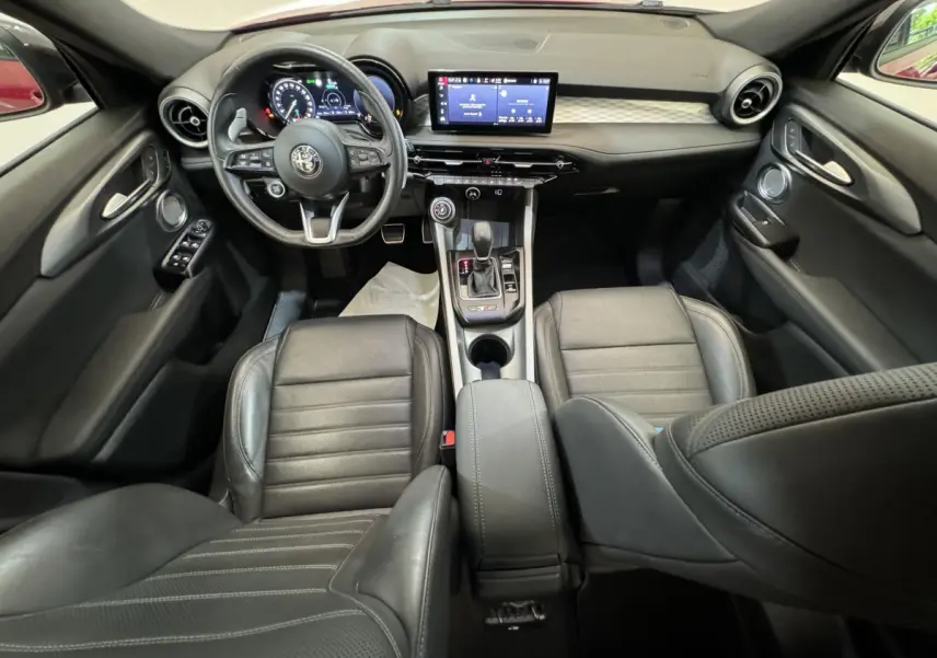 Intérieur noir de l'Alfa Romeo Tonale 2023, vue avant centrée sur tableau de bord et console centrale moderne.