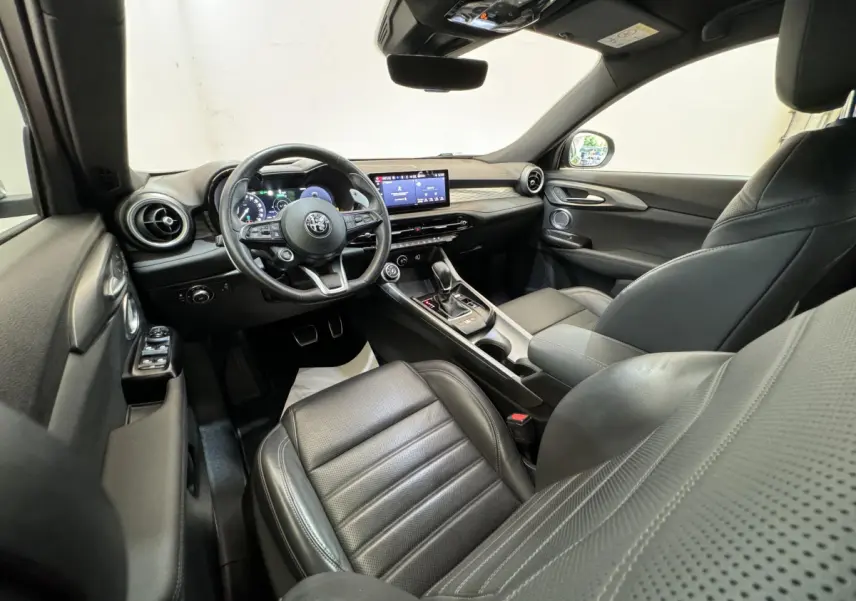 Intérieur noir de l'Alfa Romeo Tonale 2023, vue côté conducteur, volant cuir et écran tactile central visible.