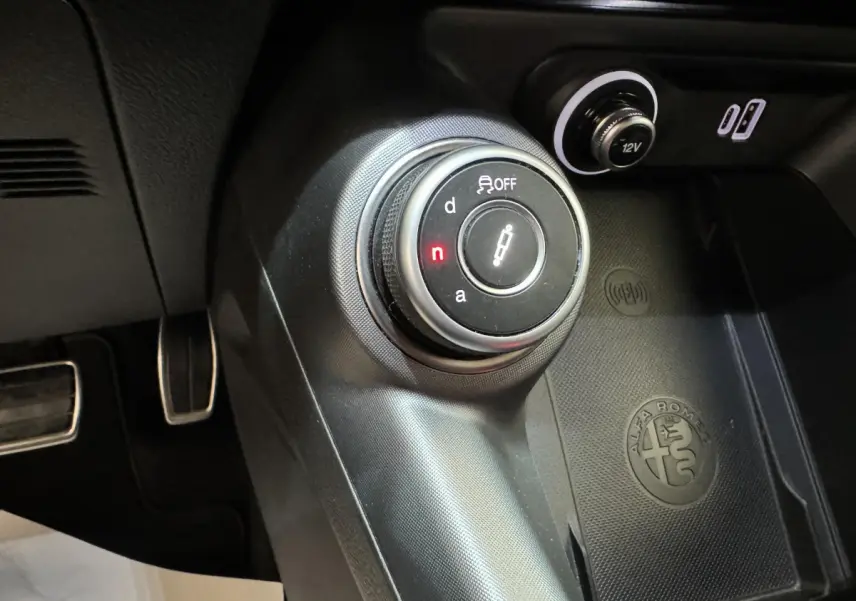 Gros plan sur la molette de sélection de boîte auto et prise 12V dans l'habitacle noir de l'Alfa Romeo Tonale rouge 2023.