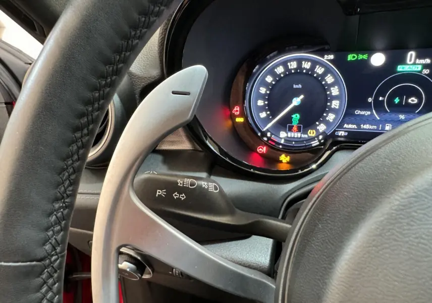 Gros plan sur le tableau de bord numérique et le volant côté gauche de l'Alfa Romeo Tonale rouge hybride rechargeable.