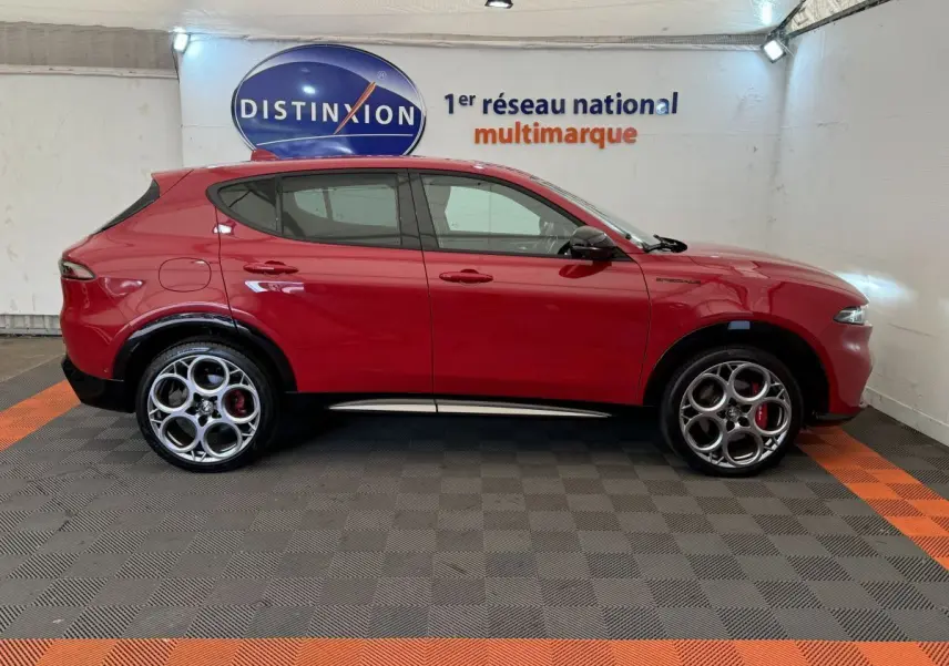 Profil droit de l'Alfa Romeo Tonale rouge 2023 avec jantes spécifiques et logo Edizione Speciale visible sur l'aile avant.