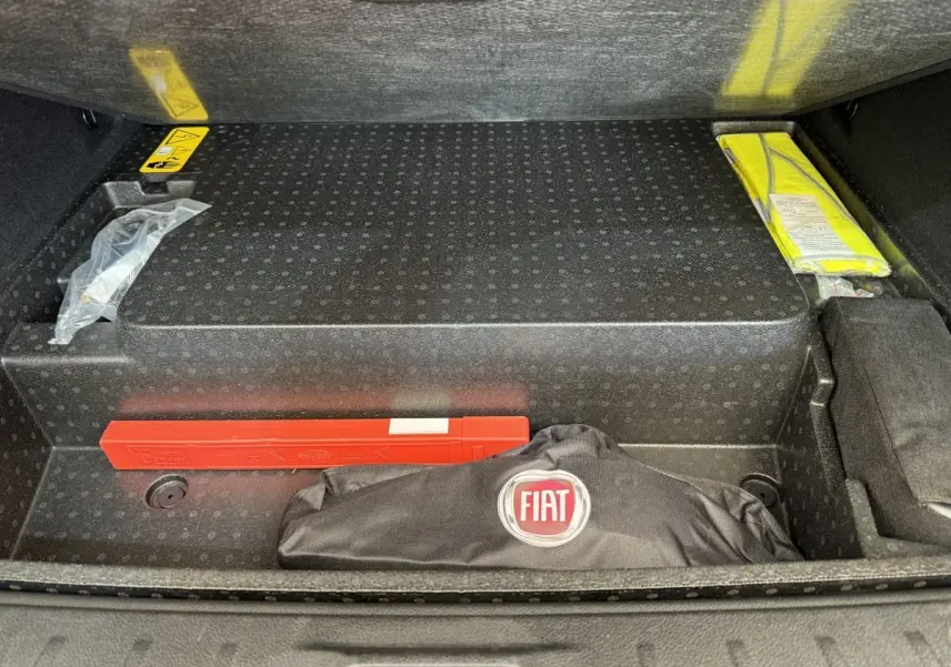 Coffre ouvert d'Alfa Romeo Tonale rouge, vue plongeante sur rangement avec trousse FIAT et triangle de signalisation.