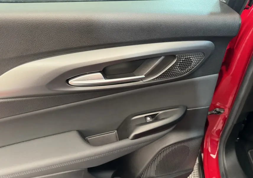 Détail de la porte côté gauche intérieure noire avec poignée alu et partie extérieure rouge visible d'une Alfa Romeo Tonale 2023.