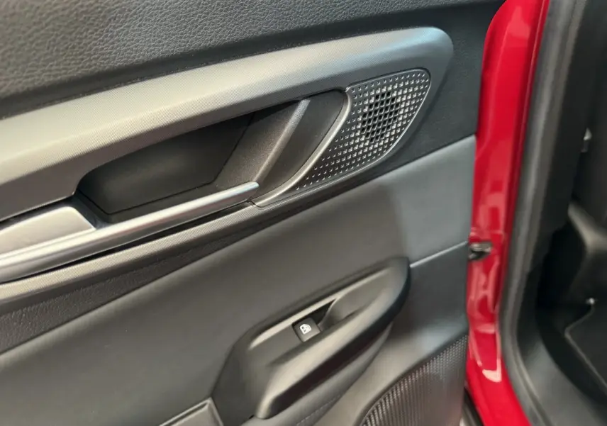 Gros plan sur la porte côté gauche rouge de l'Alfa Romeo Tonale 2023, avec poignée et commande de vitre noire.