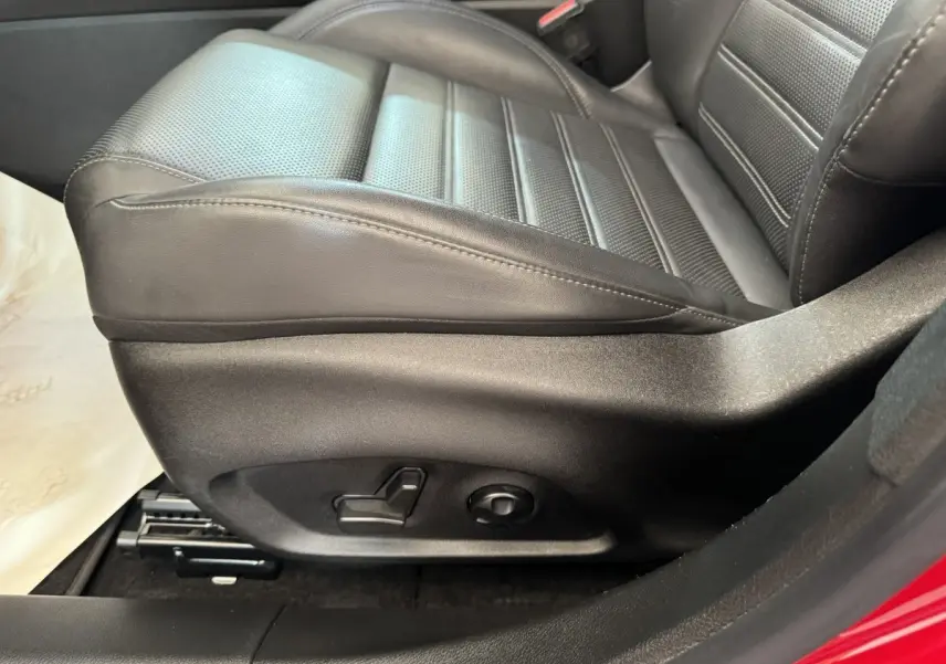 Gros plan sur le siège conducteur en cuir noir de l'Alfa Romeo Tonale rouge, avec commandes électriques visibles sur le côté.