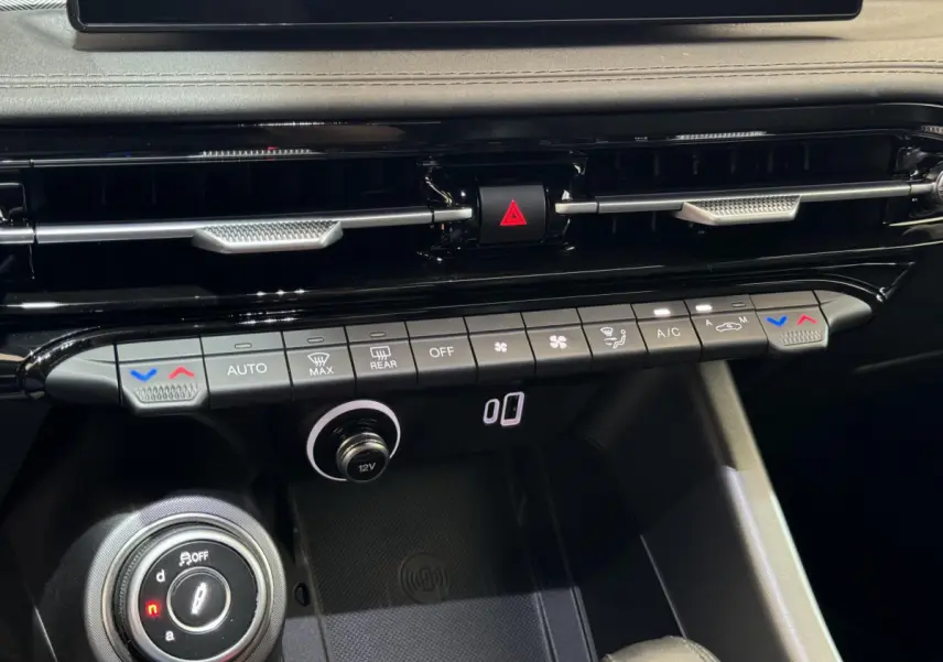 Vue rapprochée du tableau de bord noir de l'Alfa Romeo Tonale rouge, montrant les commandes de climatisation et la molette de sélection.