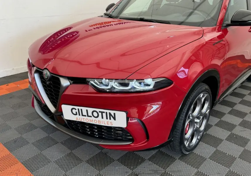 Vue 3/4 avant droit d'une Alfa Romeo Tonale rouge avec calandre caractéristique et jantes alu spécifiques Edizione Speciale.