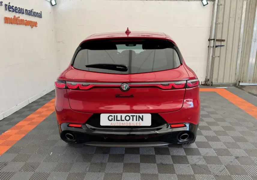 Vue arrière d'une Alfa Romeo Tonale rouge 2023 avec feux LED reliés et double sortie d'échappement noire.