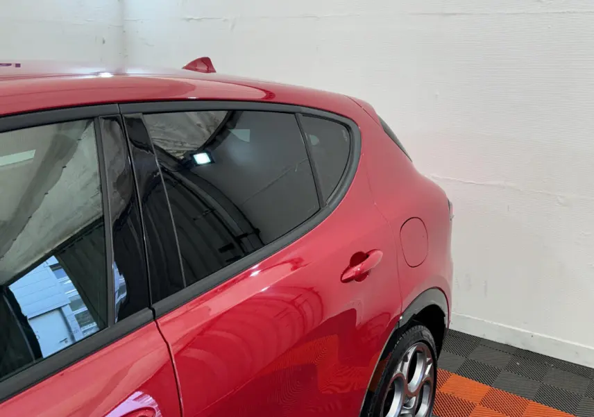 Vue côté droit arrière de l'Alfa Romeo Tonale rouge 2023 avec jantes distinctives et vitres teintées.