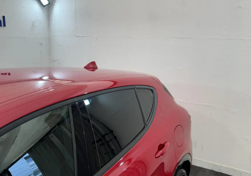 Vue côté droit arrière d'une Alfa Romeo Tonale rouge avec vitres teintées et antenne requin sur le toit