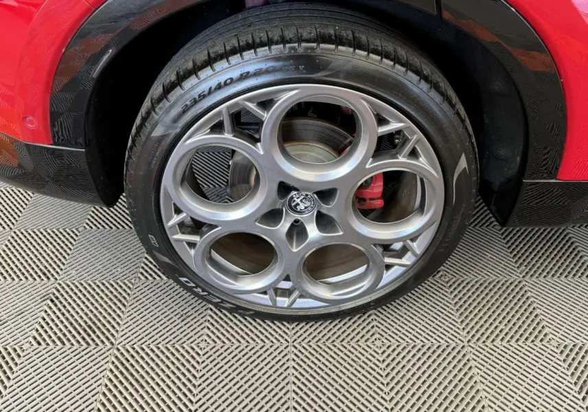 Gros plan sur la roue avant droite rouge d'Alfa Romeo Tonale avec jante en alliage à cercles entrelacés.