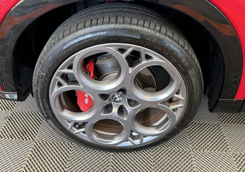 Gros plan sur la roue avant gauche rouge d'un Alfa Romeo Tonale 2023 avec étrier de frein rouge et jante distinctive.