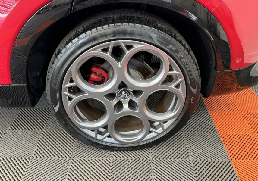 Gros plan sur la roue arrière droite de l'Alfa Romeo Tonale rouge avec jante alu distinctive et pneu Pirelli P Zero.