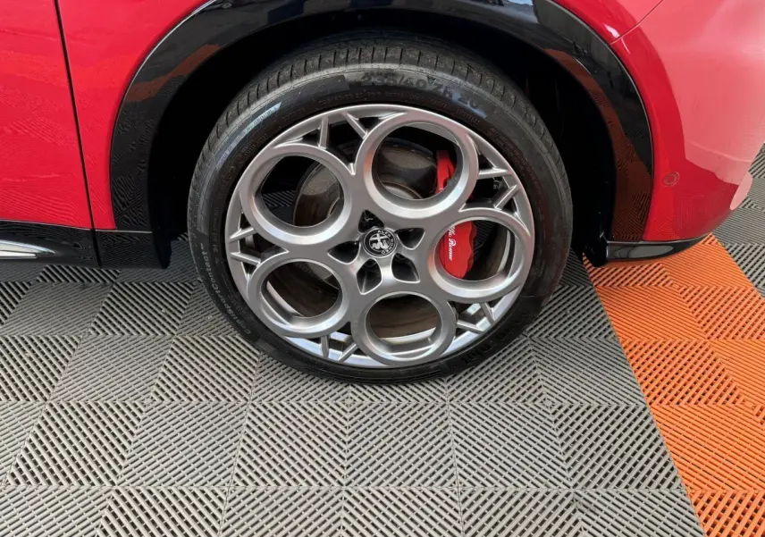 Gros plan sur la roue arrière droite rouge d'une Alfa Romeo Tonale 1.3T PHEV avec jante alu à cinq cercles et étrier rouge visible.
