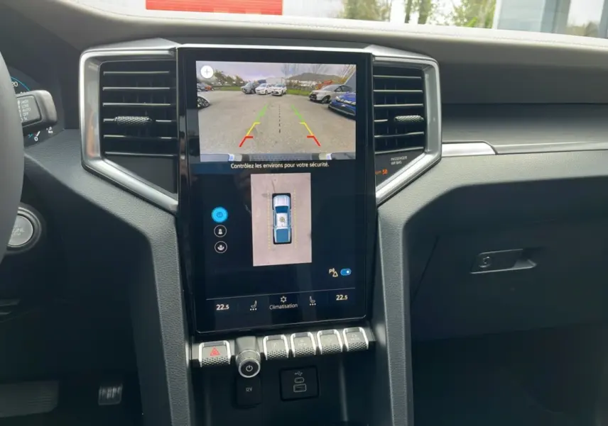 Vue intérieure du tableau de bord du Volkswagen Amarok V6 2025 avec écran tactile affichant la caméra de recul et commandes climatisation.