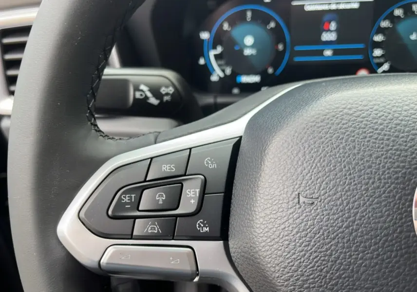 Gros plan sur le volant noir du Volkswagen Amarok Simple Cabine 2025, avec commandes de régulateur de vitesse visibles.