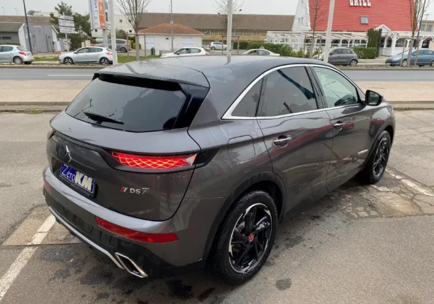 Vue 3/4 arrière droite du DS7 Crossback E-Tense gris platinium avec feux arrière LED et jantes noires brillantes.