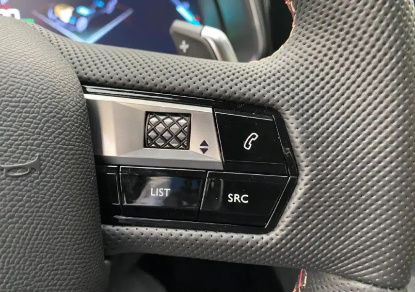 Gros plan sur les commandes gauche du volant perforé du DS7 Crossback E-Tense 2021, avec boutons LIST et SRC visibles.
