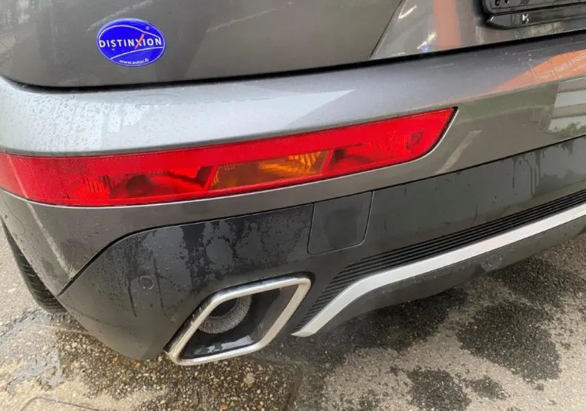 Gros plan sur le feu arrière gauche et la sortie d'échappement chromée d'un DS7 Crossback gris platinium.