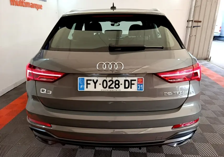 Vue arrière d'un Audi Q3 gris foncé avec feux LED allumés et plaques d'immatriculation françaises visibles.