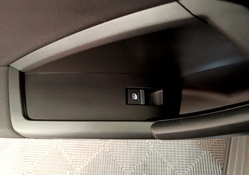 Bouton de commande de lève-vitre sur la portière côté conducteur de l'Audi Q3 gris foncé, vue rapprochée intérieure.