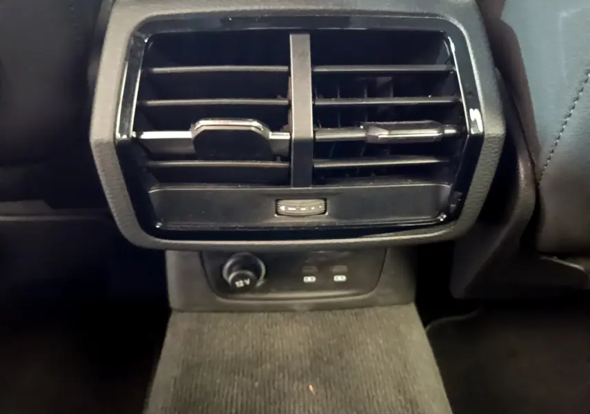 Grille d'aération arrière noire avec prise 12V et ports USB dans l'Audi Q3 gris foncé, vue rapprochée intérieure.