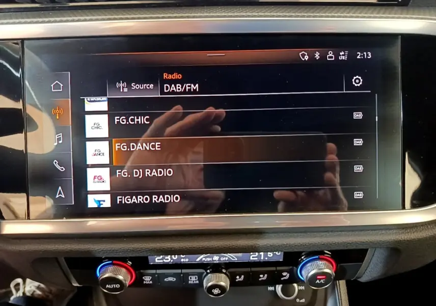 Écran tactile central affichant les stations radio DAB/FM dans l’habitacle d’un Audi Q3 gris foncé.