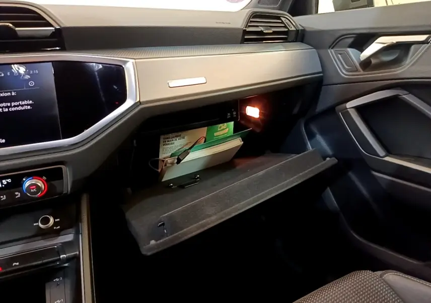 Vue intérieure côté passager de l'Audi Q3 35 TFSI 2021 avec boîte à gants ouverte et éclairage intérieur allumé.
