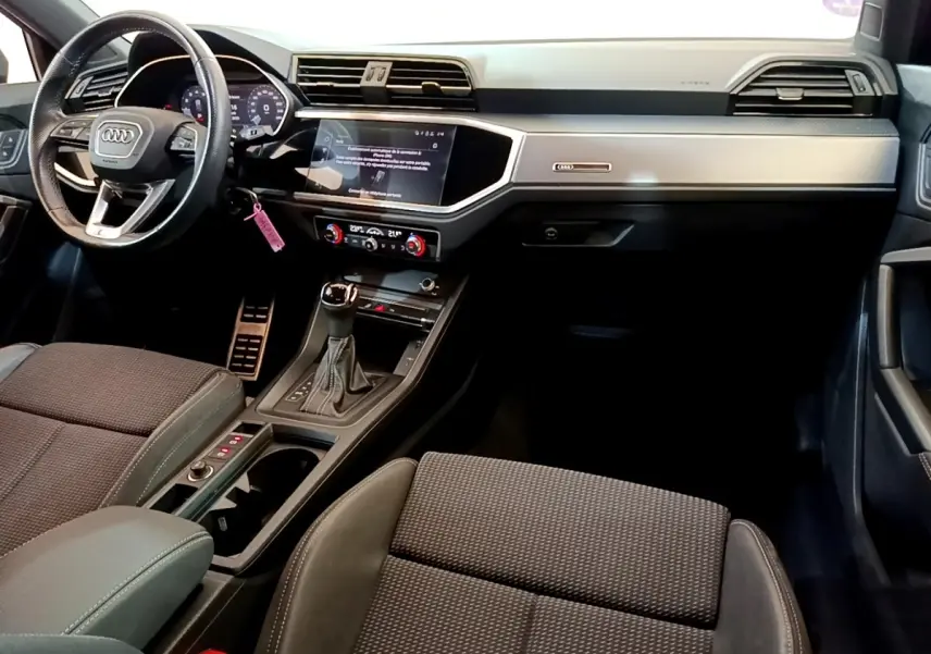 Vue intérieure avant droite de l'Audi Q3 35 TFSI S Line 2021 avec tableau de bord gris clair et volant cuir multifonctions.