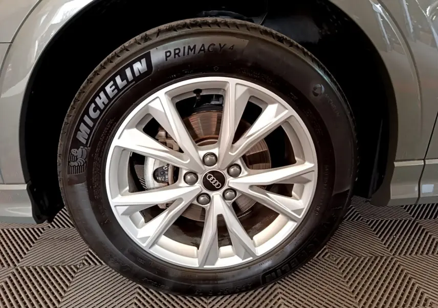 Gros plan sur la roue avant droite d’un Audi Q3 gris foncé, avec jante alliage et pneu Michelin Primacy 4.