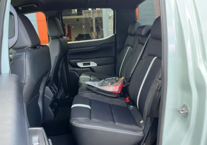 Vue latérale intérieure arrière du Ford Ranger 2.3 PHEV gris zen, sièges noirs avec surpiqûres blanches et vitres surteintées.