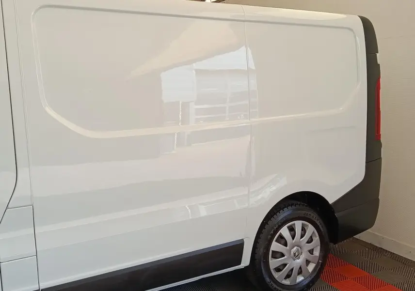 Profil droit du fourgon utilitaire Renault Trafic blanc, avec jante acier et enjoliveur gris.