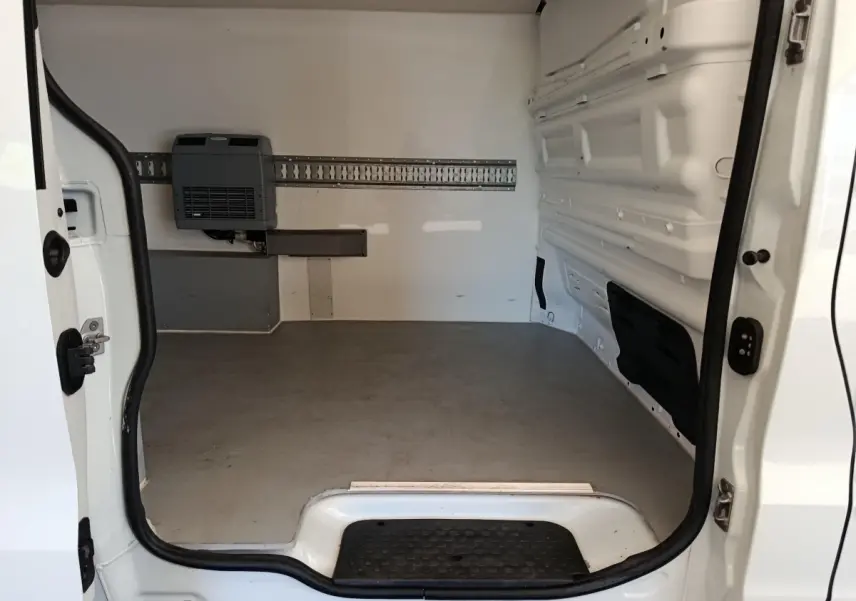 Vue intérieure arrière du fourgon blanc Renault Trafic, montrant l’espace de chargement vide avec cloison pleine.
