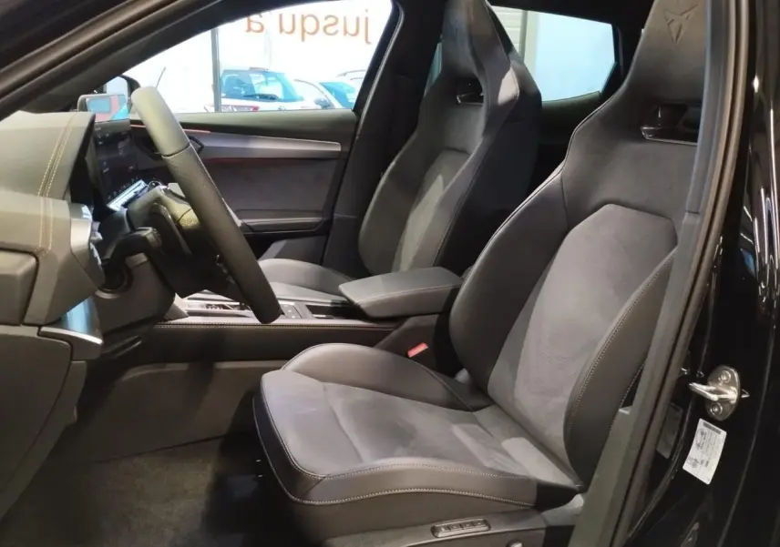 Vue intérieure côté conducteur du CUPRA Formentor noir métal 2026, sièges baquets suédine avec surpiqûres cuivrées et logo Cupra sur appuie-tête.