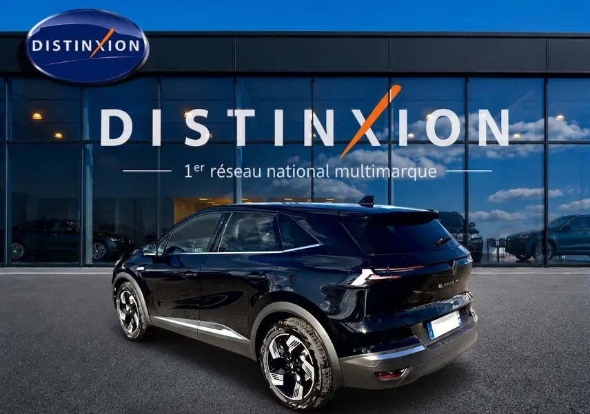 Vue 3/4 arrière droite d'un Renault Symbioz noir étoile avec jantes alu et feux arrière LED, devant un showroom Distinxion.