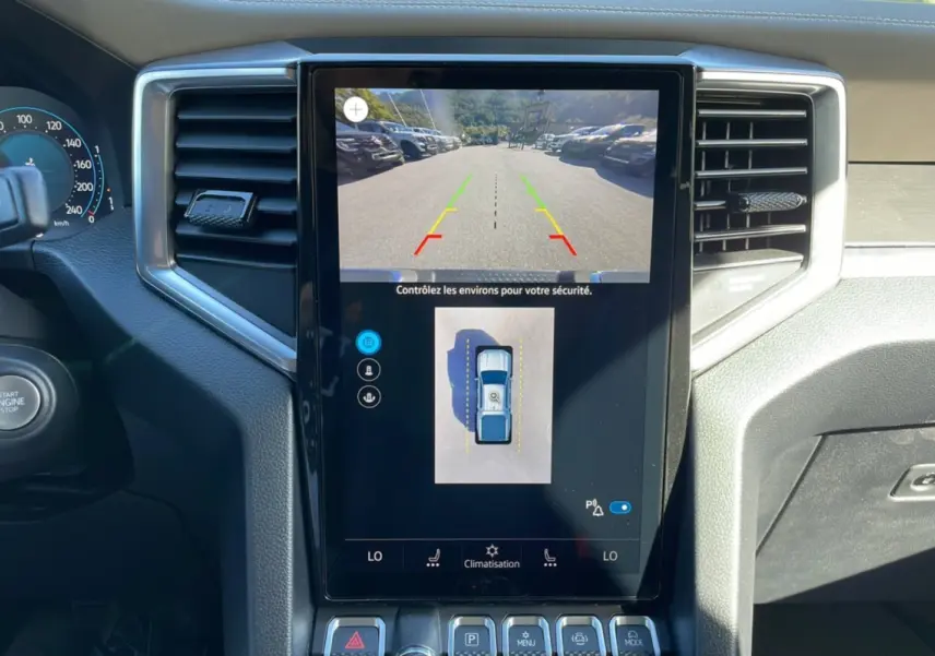 Écran central tactile affichant la caméra de recul et l'aide au stationnement du Volkswagen Amarok blanc 2025.