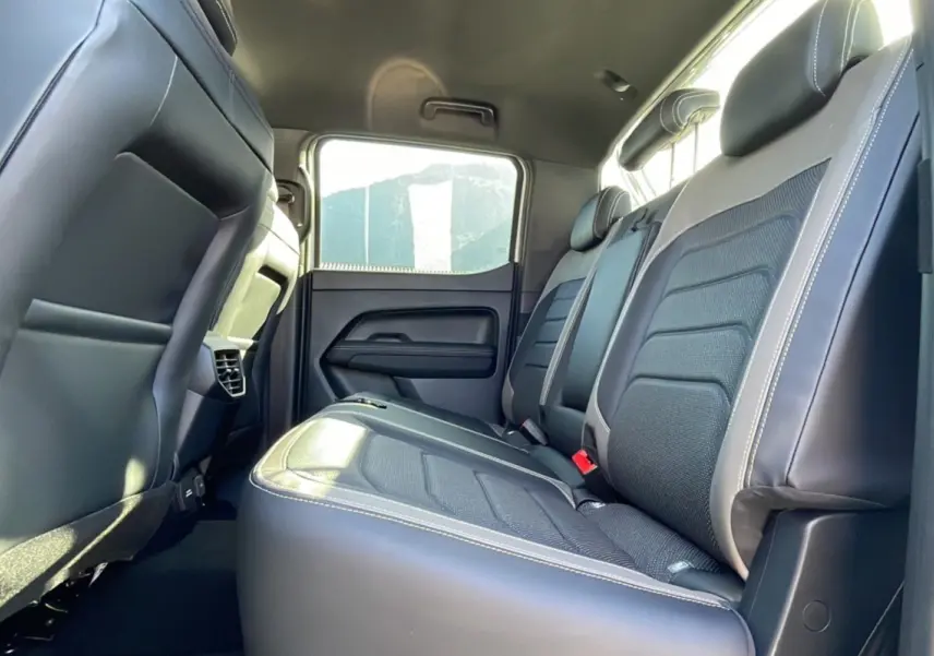 Vue intérieure arrière montrant les sièges noirs en cuir et tissu du Volkswagen Amarok Simple Cabine blanc 2025.