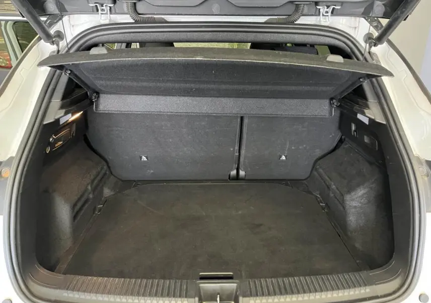 Coffre ouvert vu de l'arrière du Renault Austral blanc, avec cache-bagages relevé et intérieur noir.