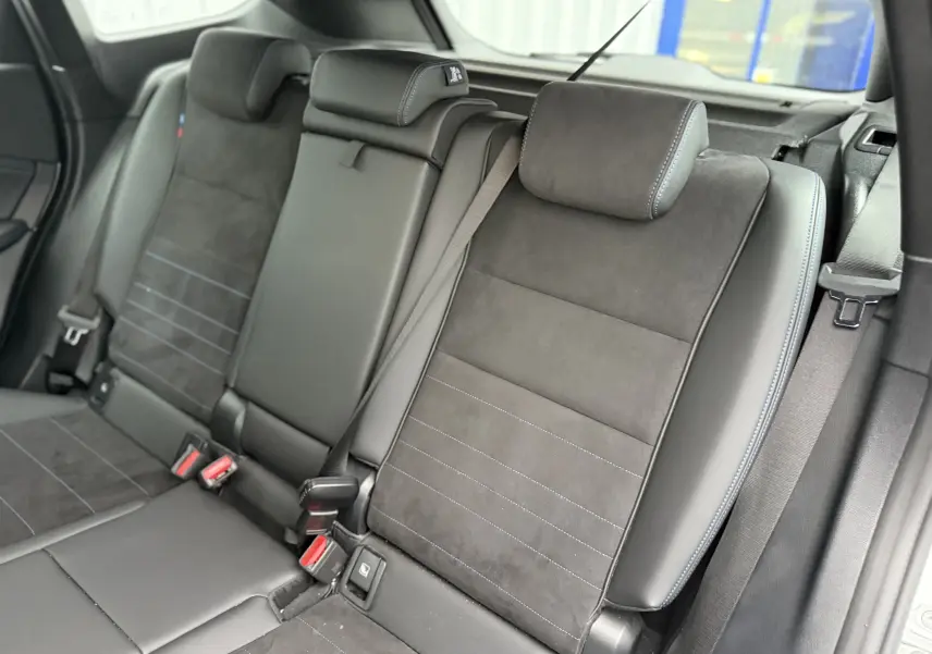 Vue rapprochée des sièges arrière en cuir noir avec surpiqûres bleues du BMW X1 18D M Sport blanc minéral 2025.