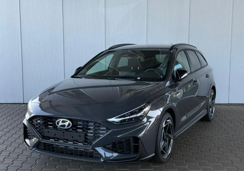 Vue 3/4 avant droite d'une Hyundai i30 SW N-Line gris foncé avec calandre hexagonale et jantes alliage distinctives.
