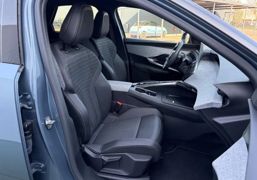 Vue intérieure côté conducteur du Peugeot 3008 bleu Ingaro 2024, sièges tissus et cuir avec tableau de bord gris clair.
