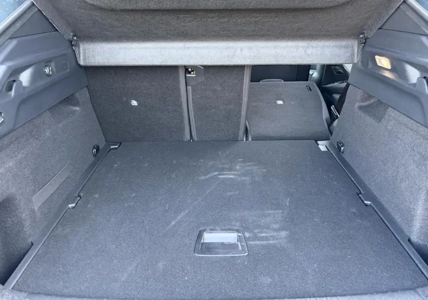 Coffre ouvert de Peugeot 3008 bleu Ingaro, vue intérieure arrière avec banquette partiellement rabattue.