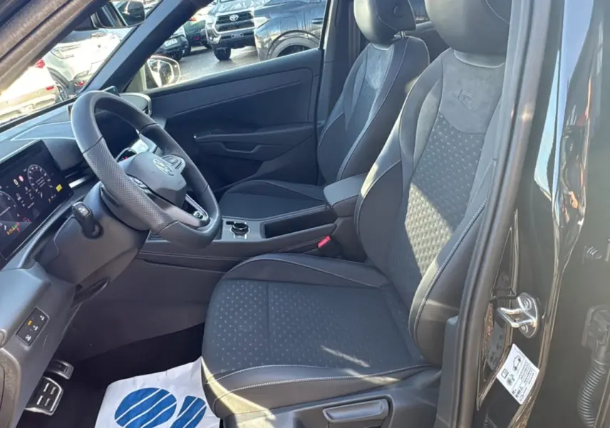 Vue intérieure côté conducteur du Volkswagen T-Roc noir ebène 2026, sièges tissu R-Line et tableau de bord digital.