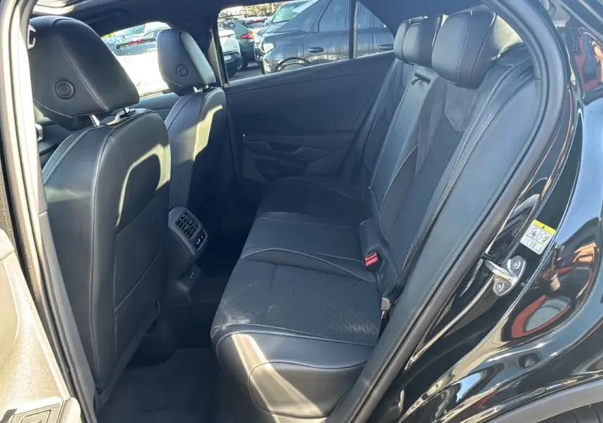 Vue intérieure côté arrière droit du Volkswagen T-Roc noir ebène, montrant la banquette arrière en tissu et cuir avec appuie-têtes.