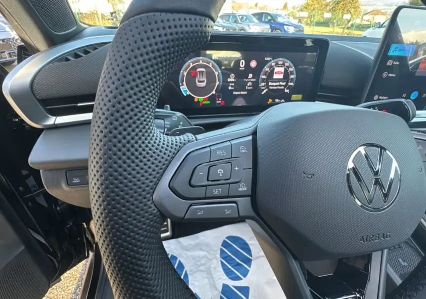 Gros plan sur le volant cuir multifonctions noir du Volkswagen T-Roc 2026 avec tableau de bord digital lumineux.