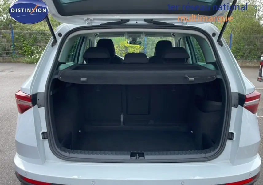 Vue arrière ouverte du Skoda Karoq blanc glacier 2025, mettant en valeur le coffre spacieux et la tablette cache-bagages.