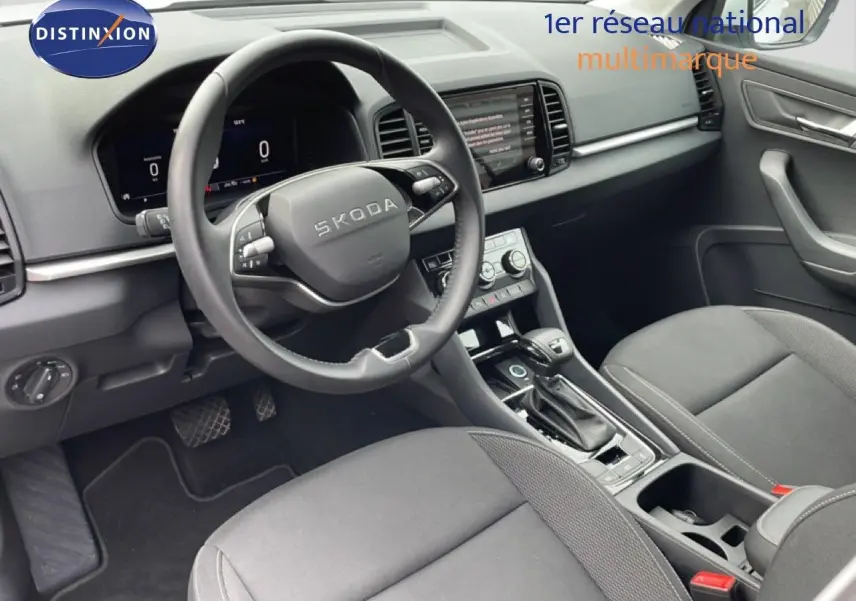 Vue intérieure côté conducteur du Skoda Karoq 2025, tableau de bord et volant noir avec écran digital et console centrale.
