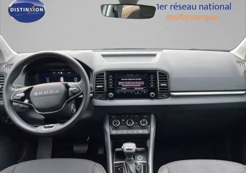 Vue intérieure frontale du tableau de bord et volant noir du Skoda Karoq blanc Glacier 2025 avec écran tactile central.