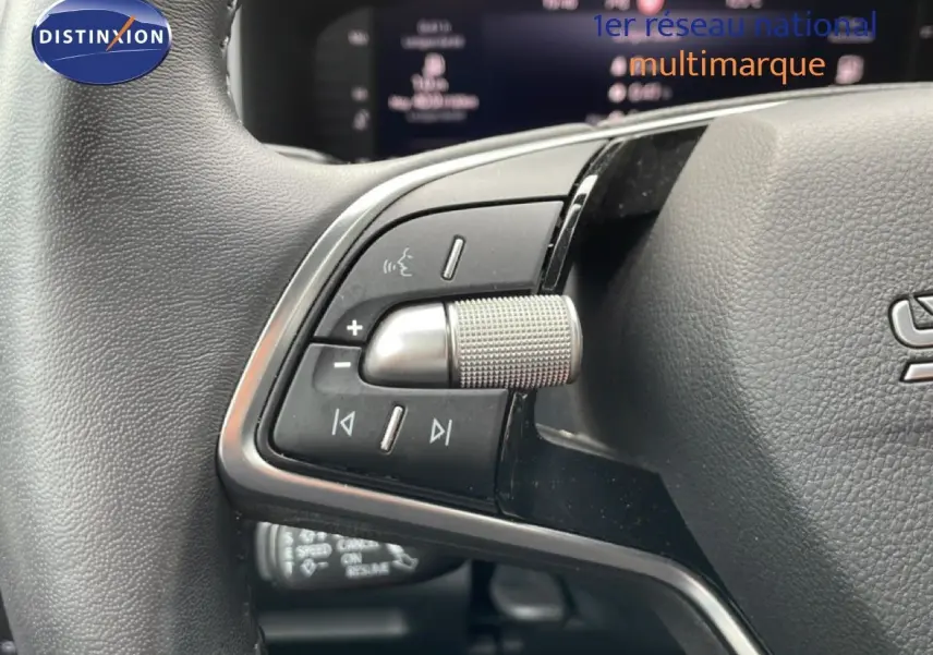 Gros plan sur les commandes multimédia au volant d’un Skoda Karoq blanc glacier 2025, version Selection.